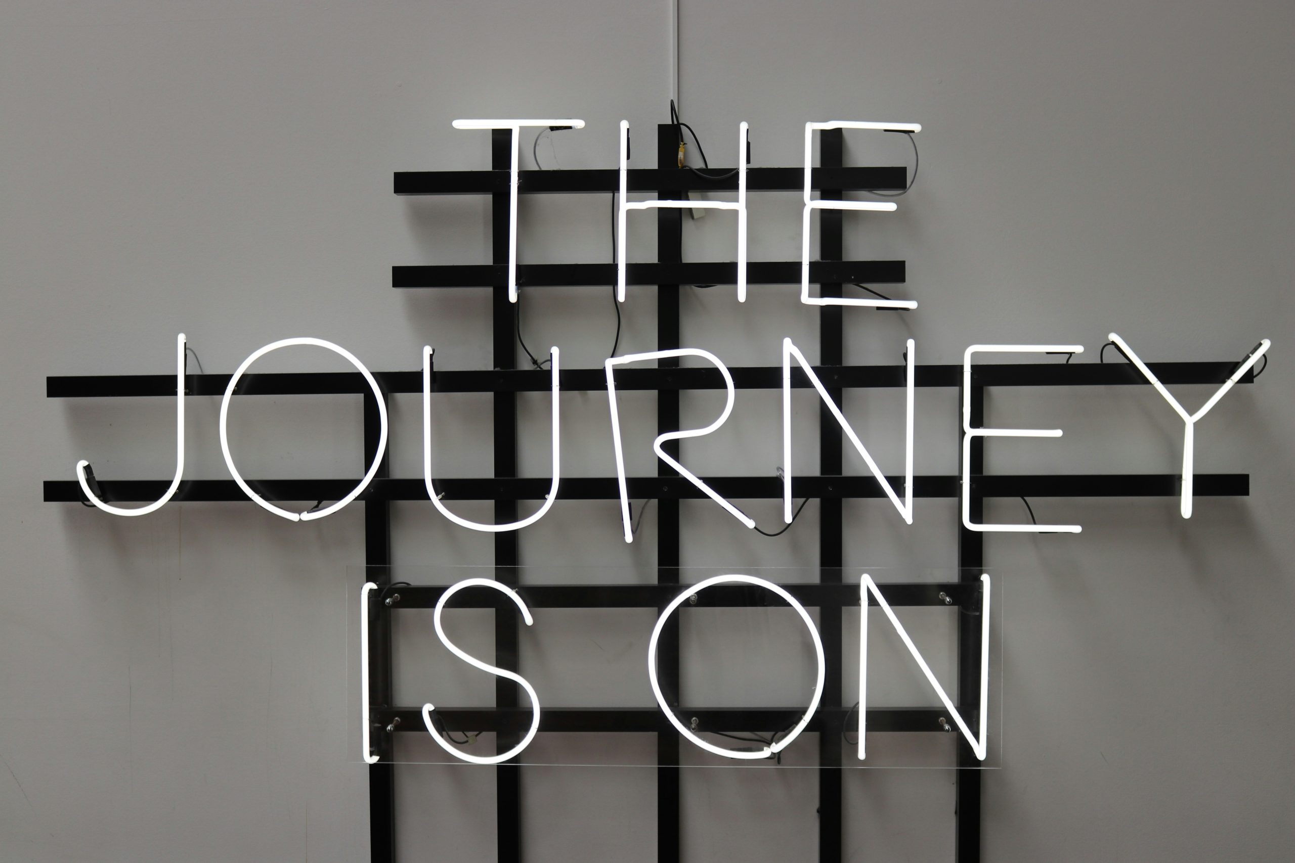 An unlit neon sign that reads "The Journey Is On" in all capital letters.
