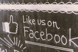 A chalkboard with "Like Us On Facebook" written on it, showing the differentiation between old-school marketing and digital advertising.